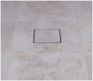 Square wet room floor gulley showing angled cuts in large ceramic tiles and a tile-in gully cover